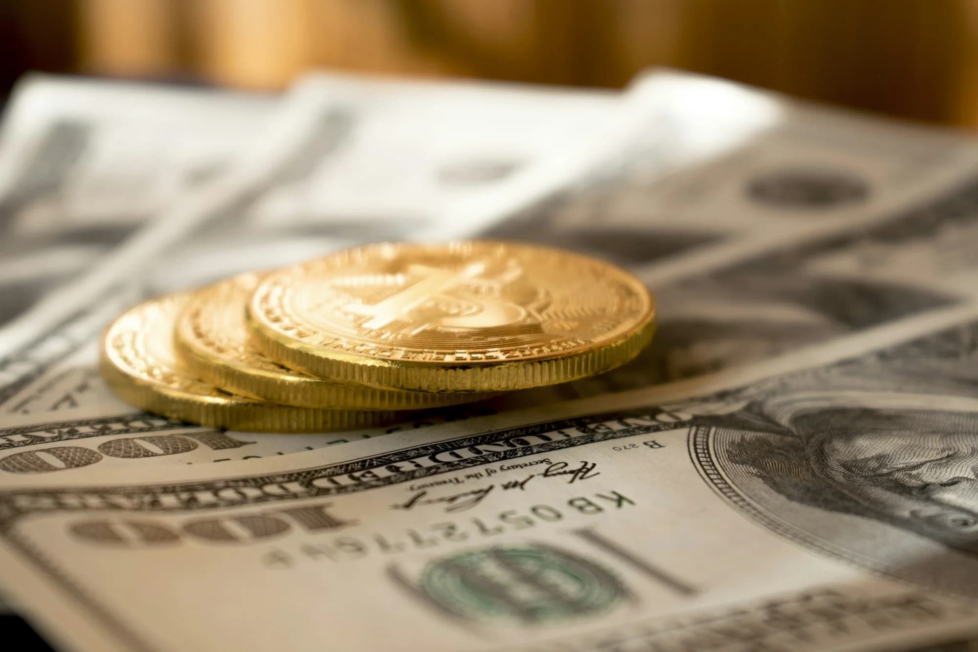 Koin emas di atas uang kertas dolar AS (Dmytro Demidko, Unsplash)