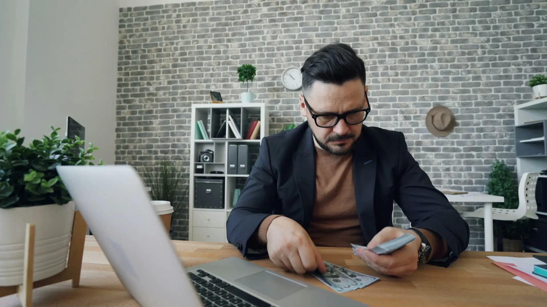 Rich entrepreneur counting money smiling sitting at office table at work - Vitaly Gariev, Unsplash