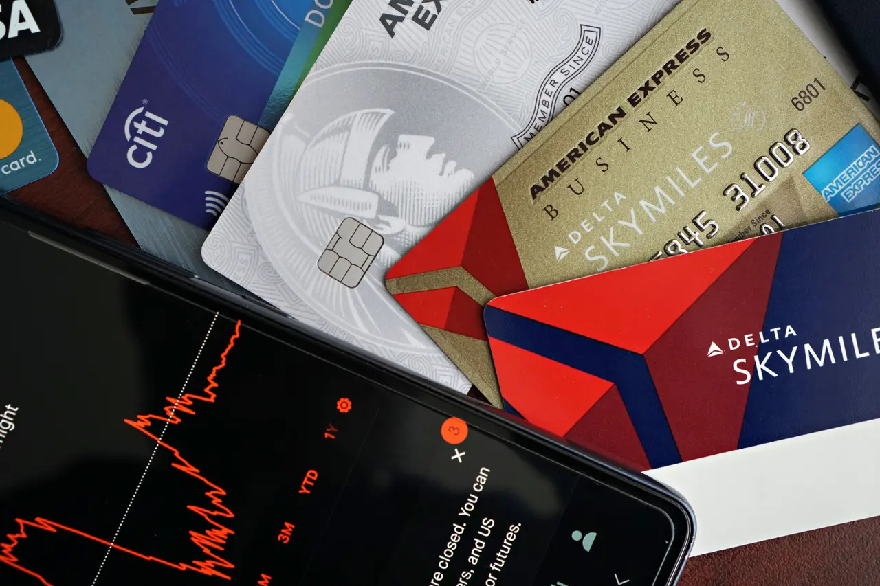 Credit cards and a phone displaying financial market analysis