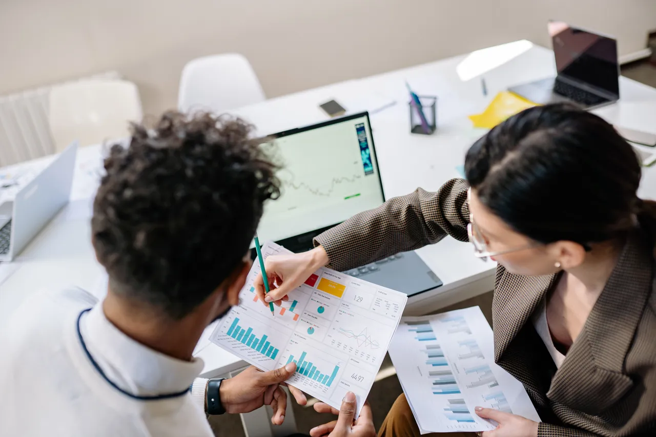 Two colleagues discussing financial charts and graphs
