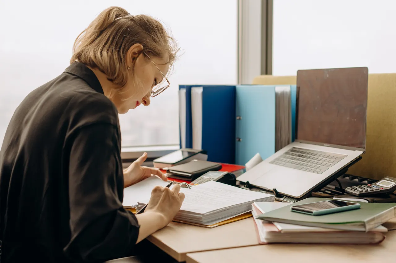 A woman reviewing notes and financial documents at a desk