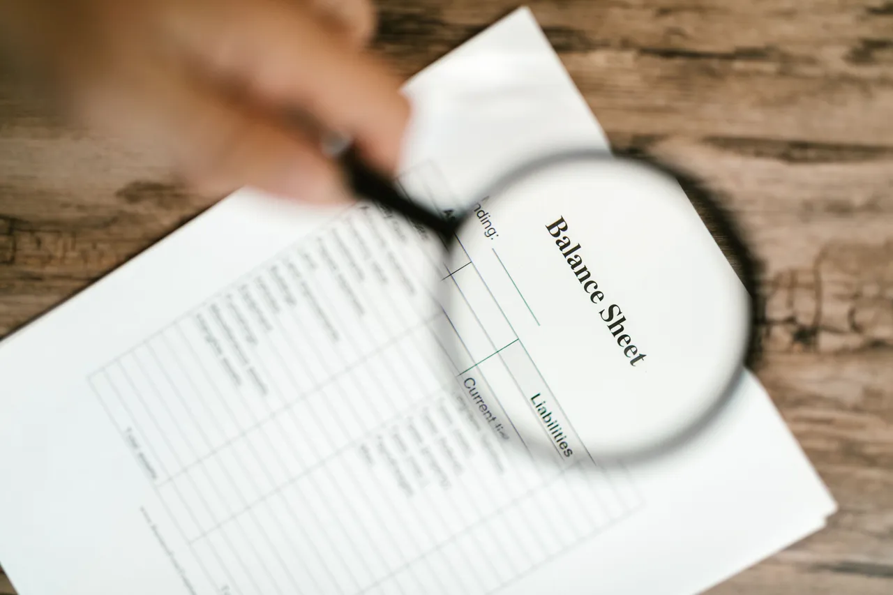 Close-up shot of a balance sheet under a magnifying glass