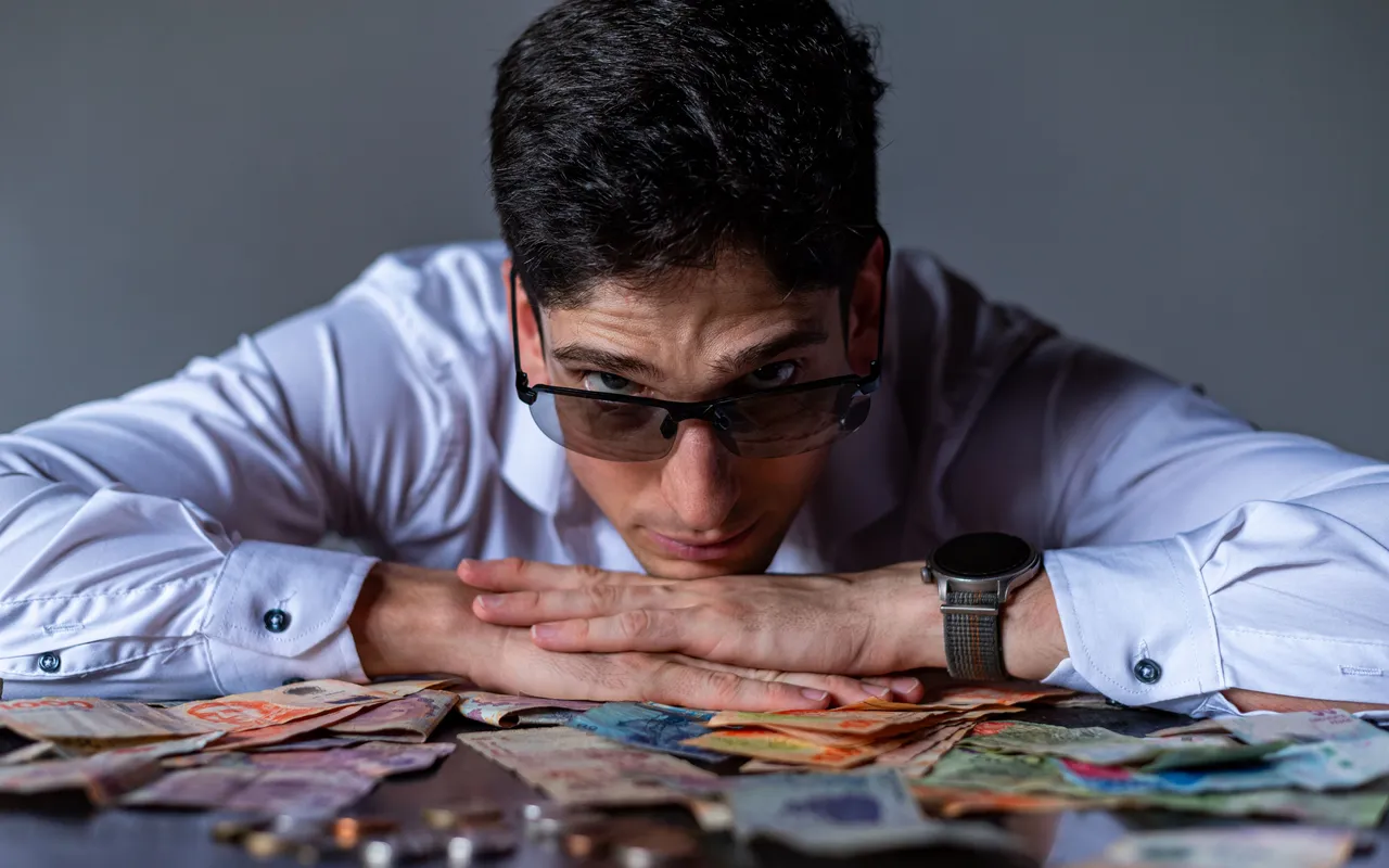 A man contemplating currency notes on a table