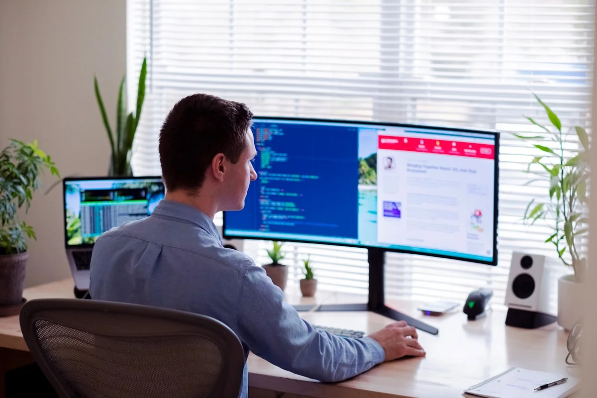 Man in gray dress shirt sitting in front of a computer monitor (Luke Peters, Unsplash)