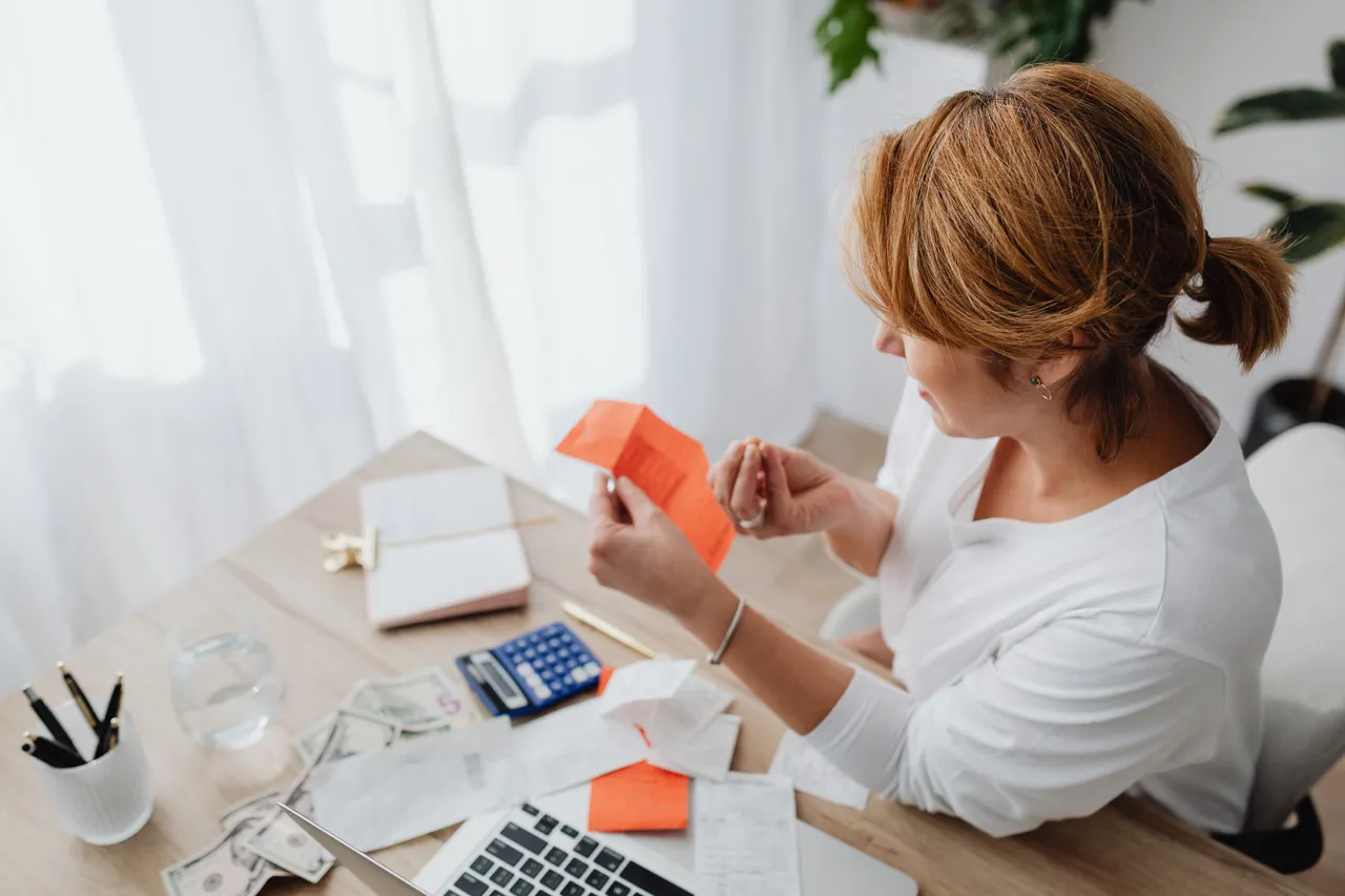 A woman working with receipts, calculator, and laptop at a desk