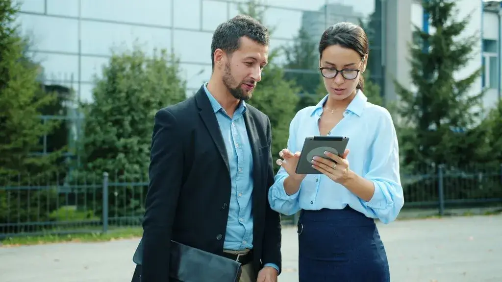 Business colleagues discuss work on tablet outdoors