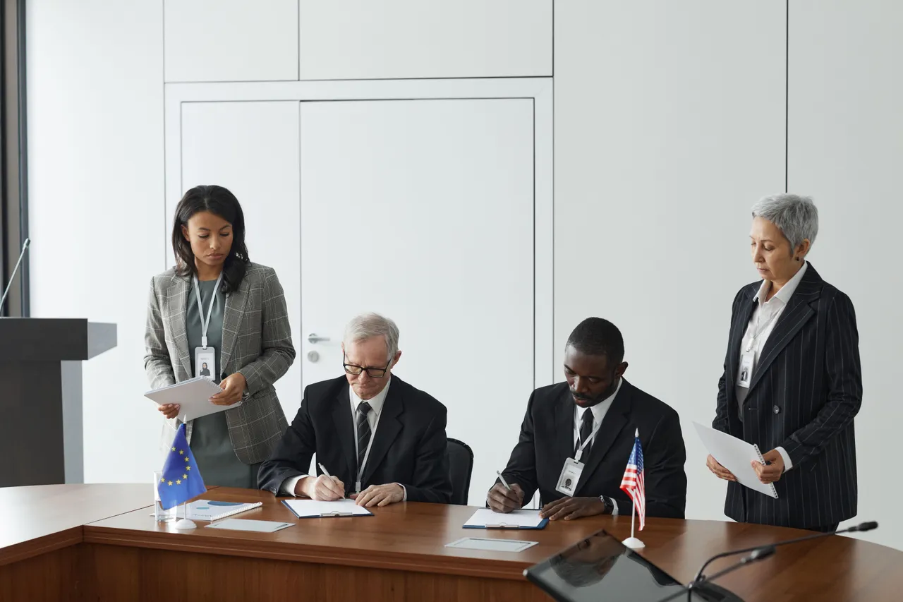 Two men sitting at a table signing papers